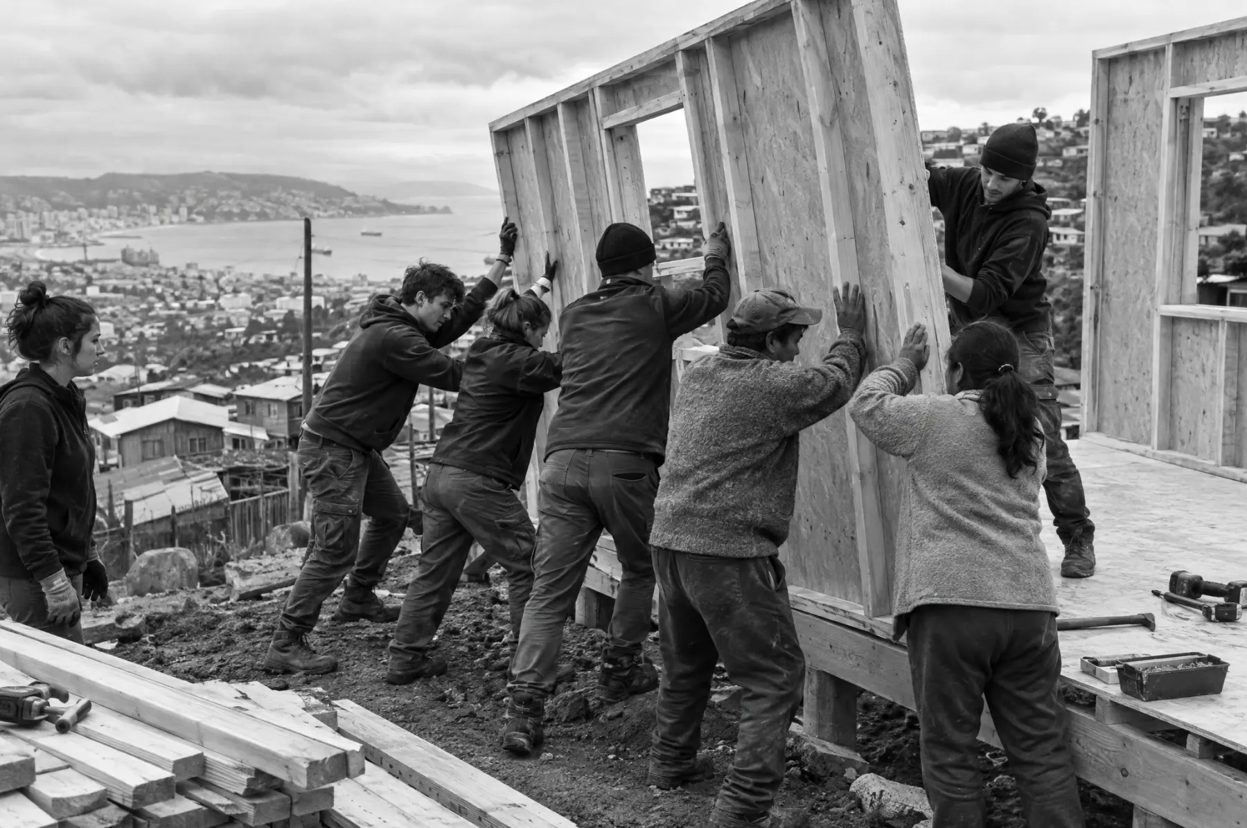Voluntarios y una familia levantan los muros de una vivienda en un cerro